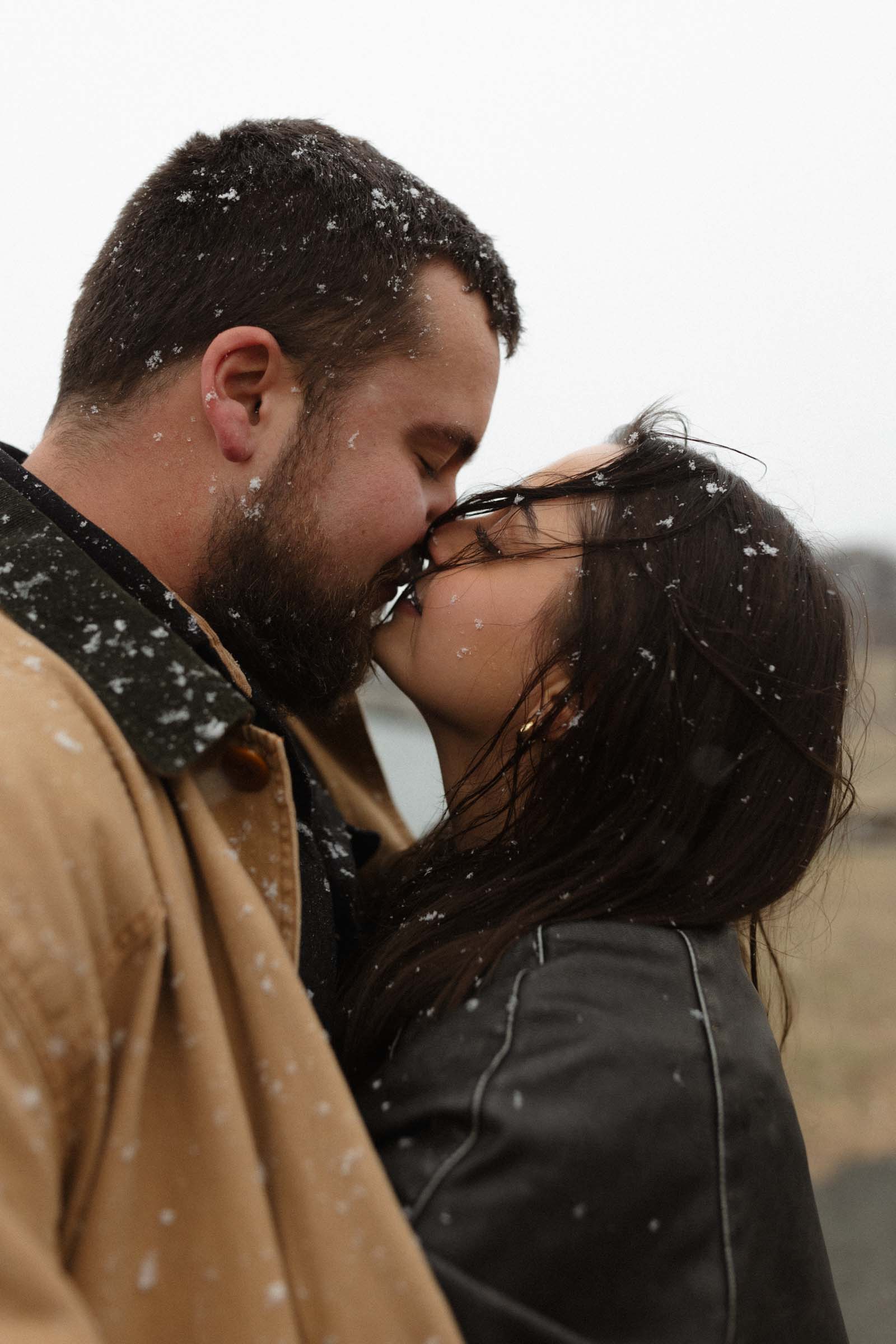 couple almost kissing, covered in snowflakes, in Boston MA