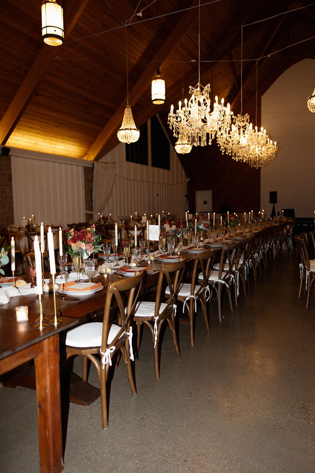 Long candlelit reception tables beneath vaulted wood ceilings and crystal chandeliers at one of the most romantic wedding venues in Rhode Island.