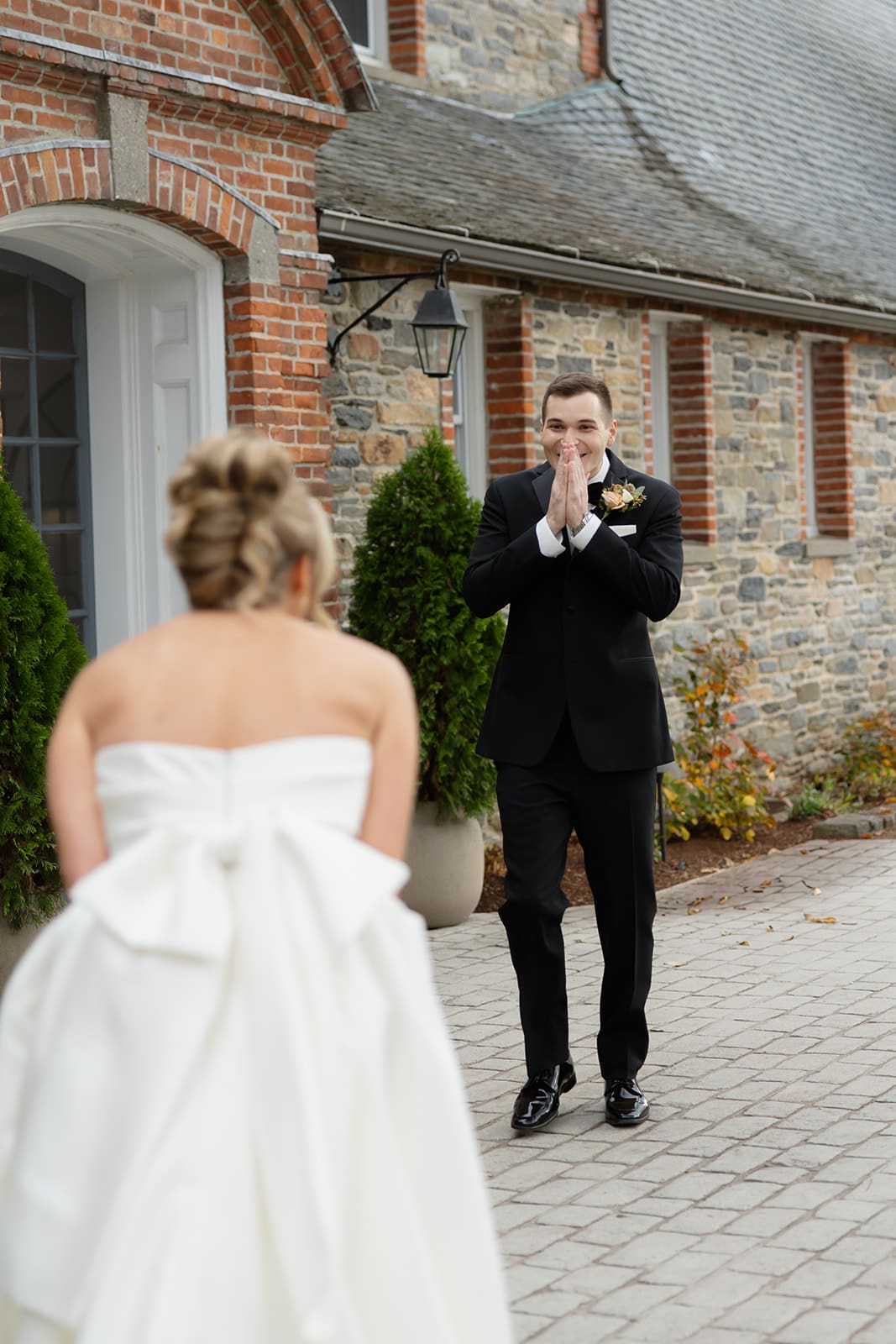 Groom covering his face in emotional reaction during first look outside a historic vineyard estate wedding in Rhode Island.