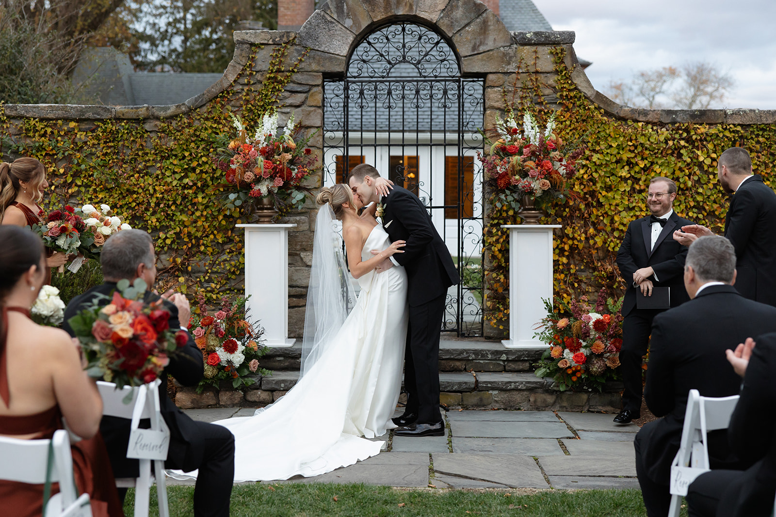 Bride and groom sharing their first kiss beneath ivy-covered stone arch at one of the most romantic wedding venues in Rhode Island.