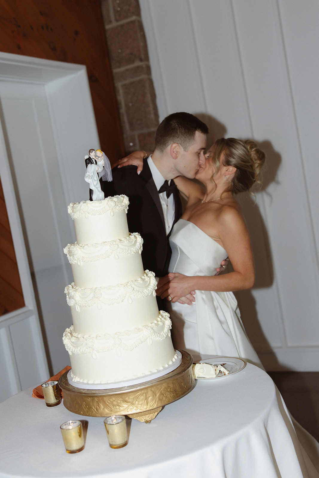Bride and groom kissing beside their wedding cake at one of the most romantic wedding venues in Rhode Island.