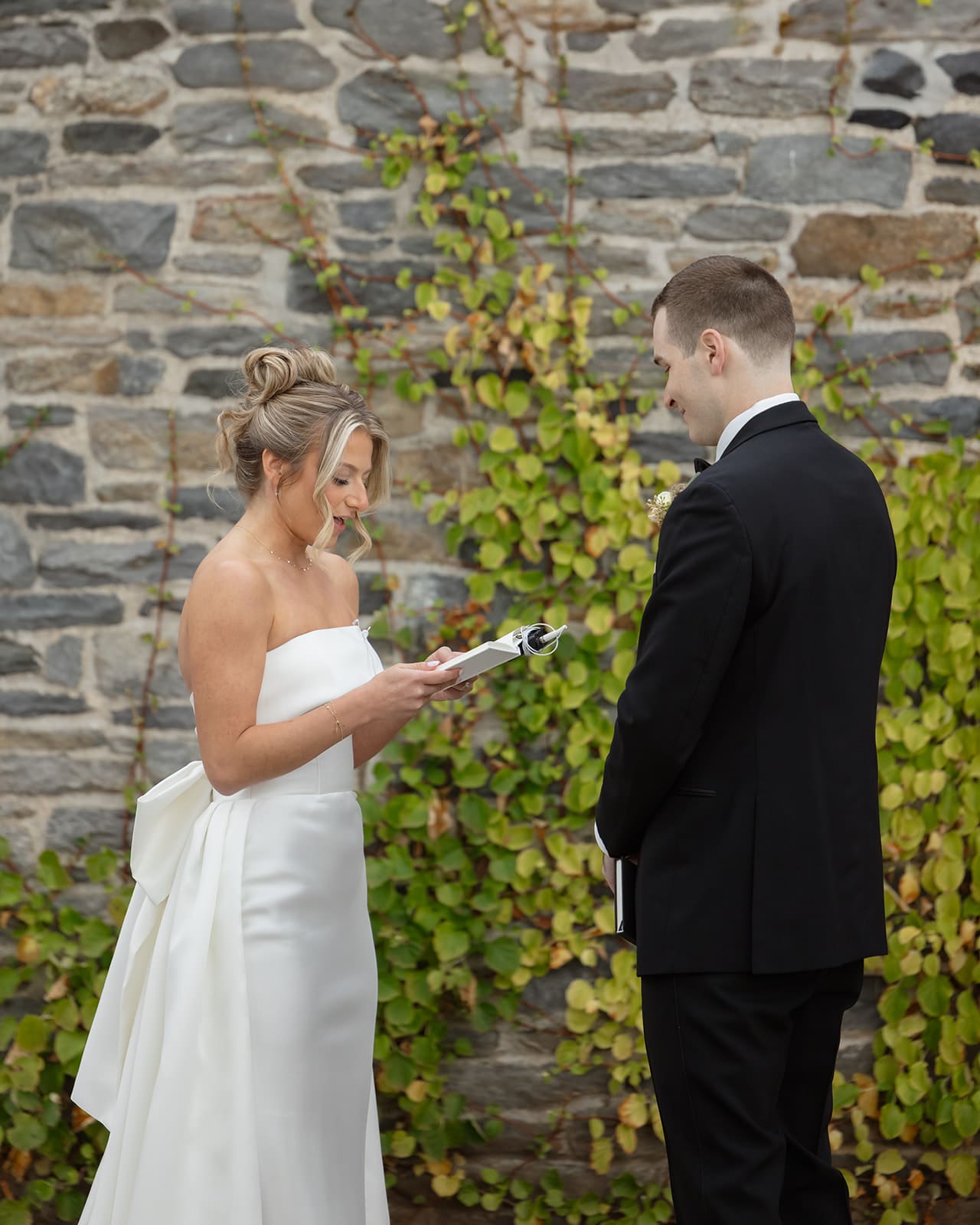 Bride reading private vows to groom against ivy-covered stone wall at one of the most romantic wedding venues in Rhode Island.
