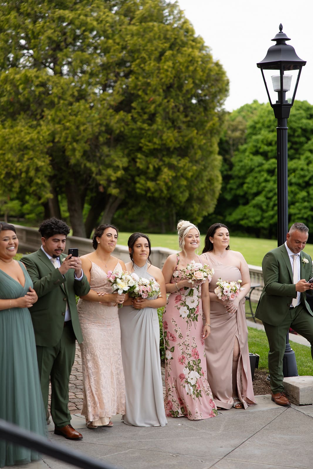 Bridesmaids and groomsmen stand together holding bouquets, their dresses and suits adding texture to a colorful wedding palette.
