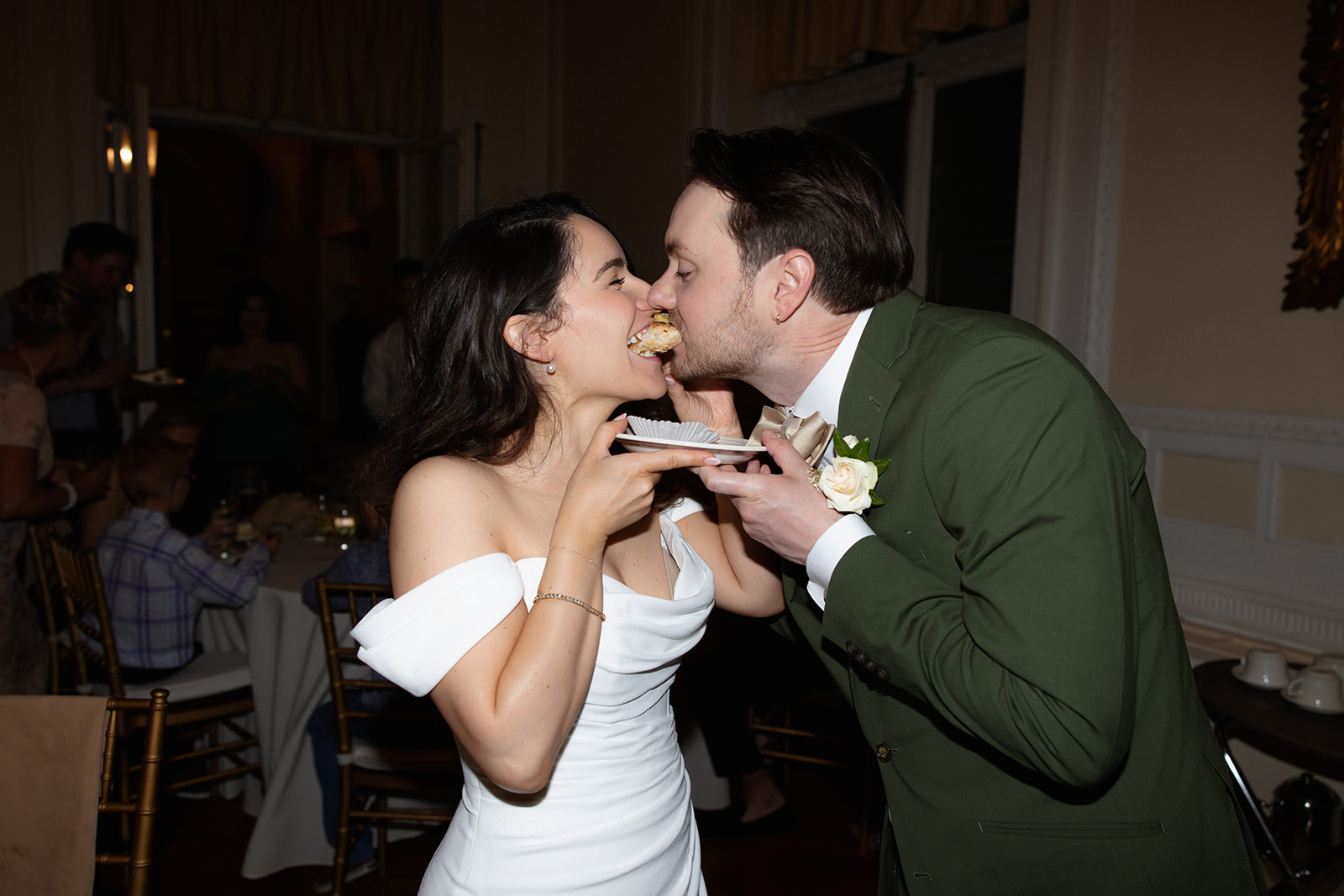 The couple shares a playful bite of dessert during their reception, a candid moment from a colorful wedding evening.
