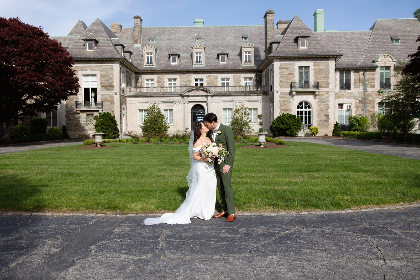 The couple stands together in front of the estate, framed by the architecture during a colorful wedding afternoon.
