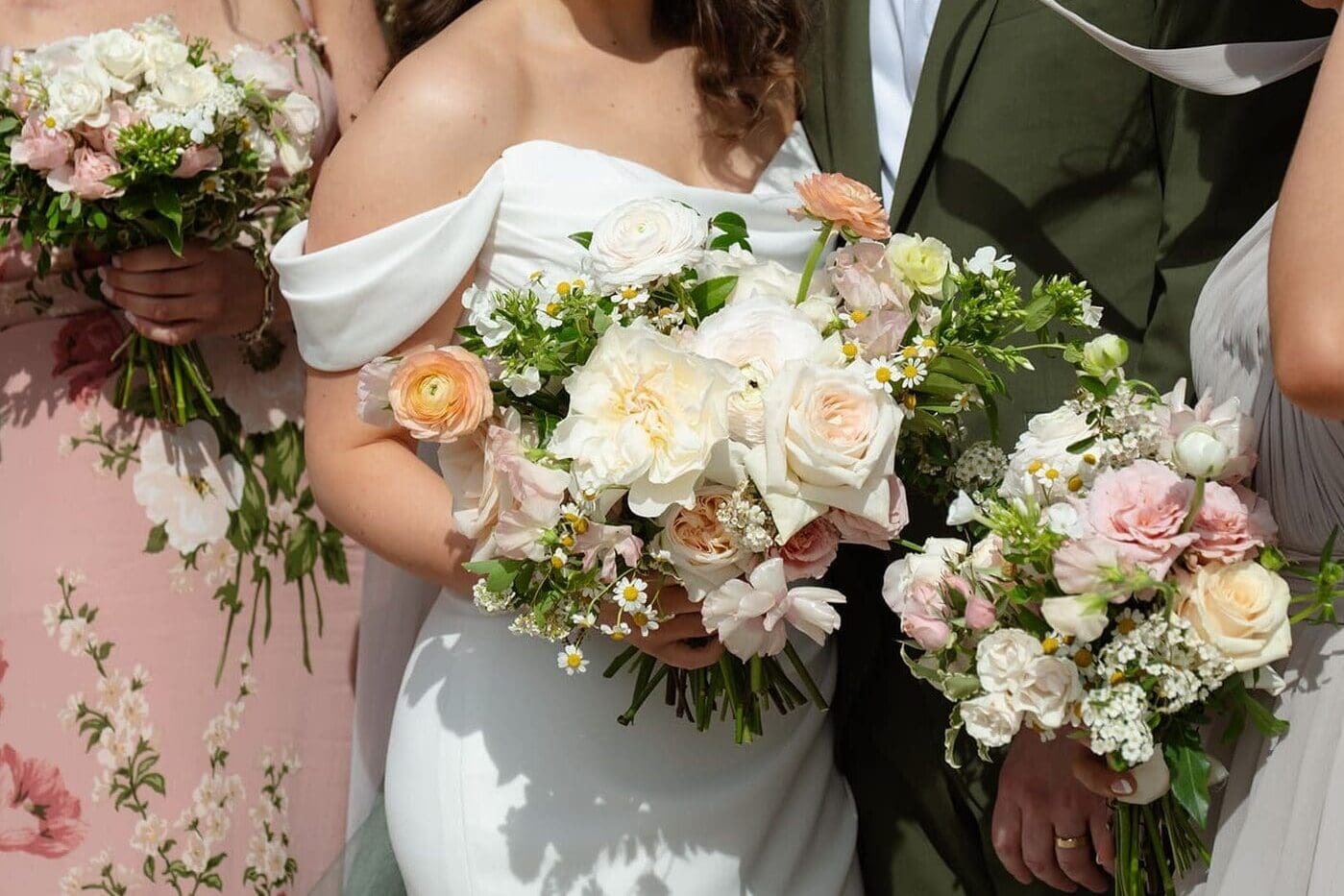 A close view of the bride’s bouquet with soft garden florals in blush, cream, and green during a colorful wedding.
