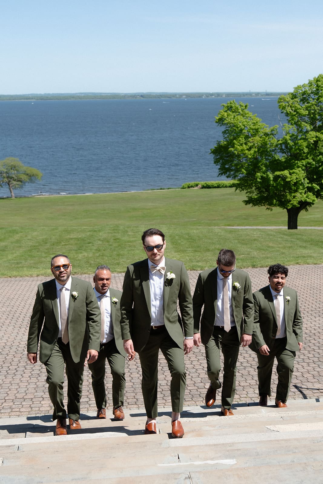 The groomsmen walk up the steps overlooking the water, marking the start of a colorful wedding day.
