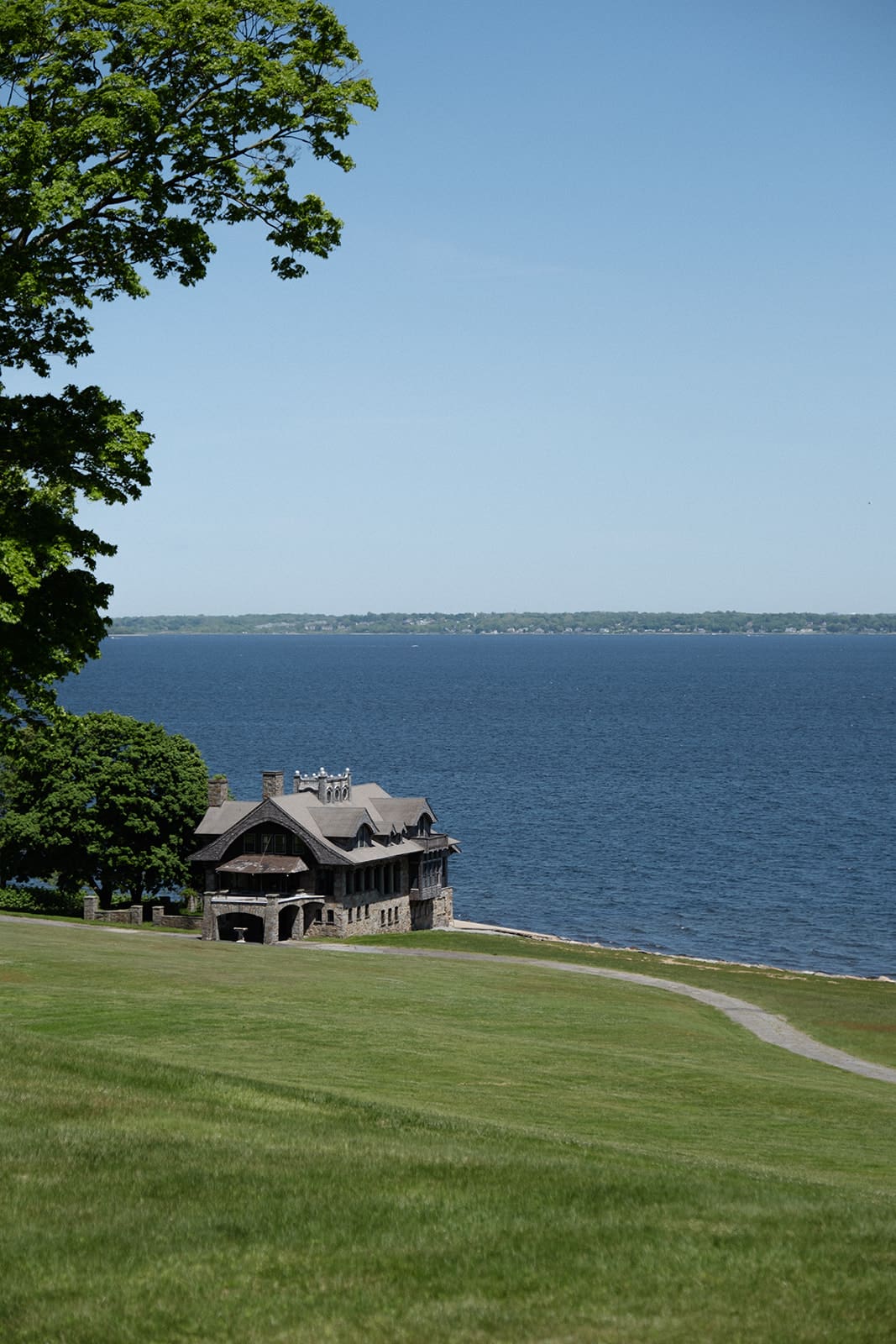The coastline stretches beyond the property, with a small stone building overlooking the water during a colorful wedding weekend.
