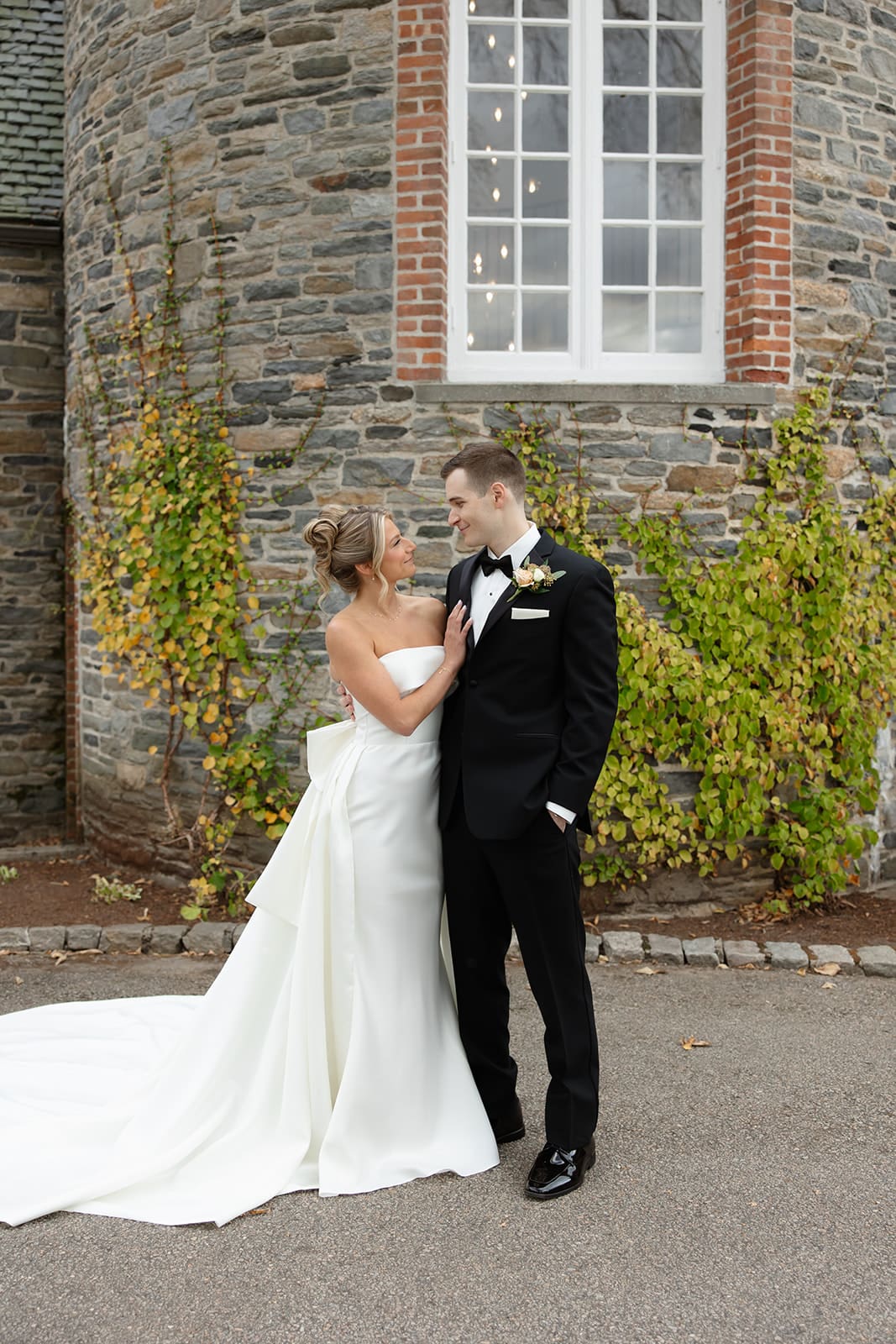 Bride and groom standing together outside a historic stone estate surrounded by ivy, a beautiful example of Wedding Venues in Rhode Island.
