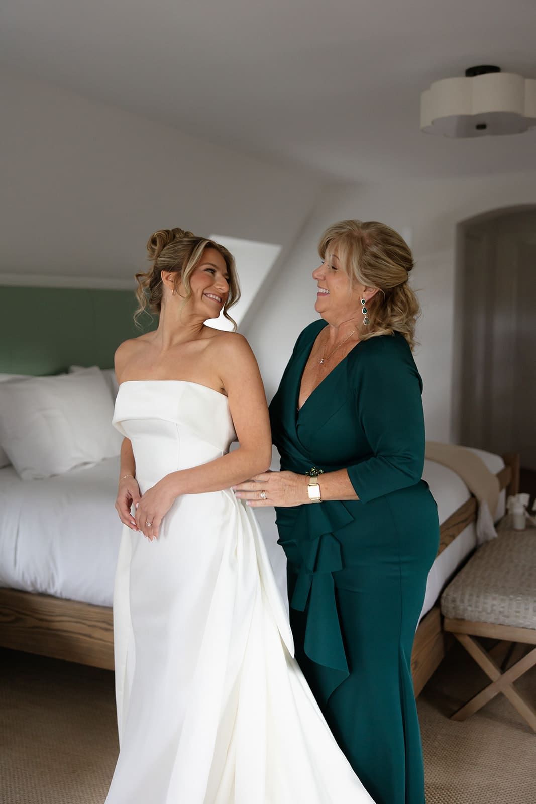 Bride smiling with her mother while getting ready in a bright bridal suite at one of the most elegant Wedding Venues in Rhode Island.
