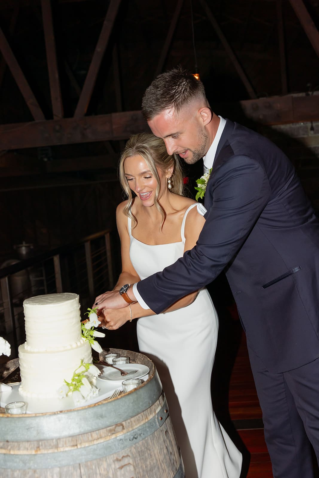 Bride and groom cutting their wedding cake together during evening reception celebration
