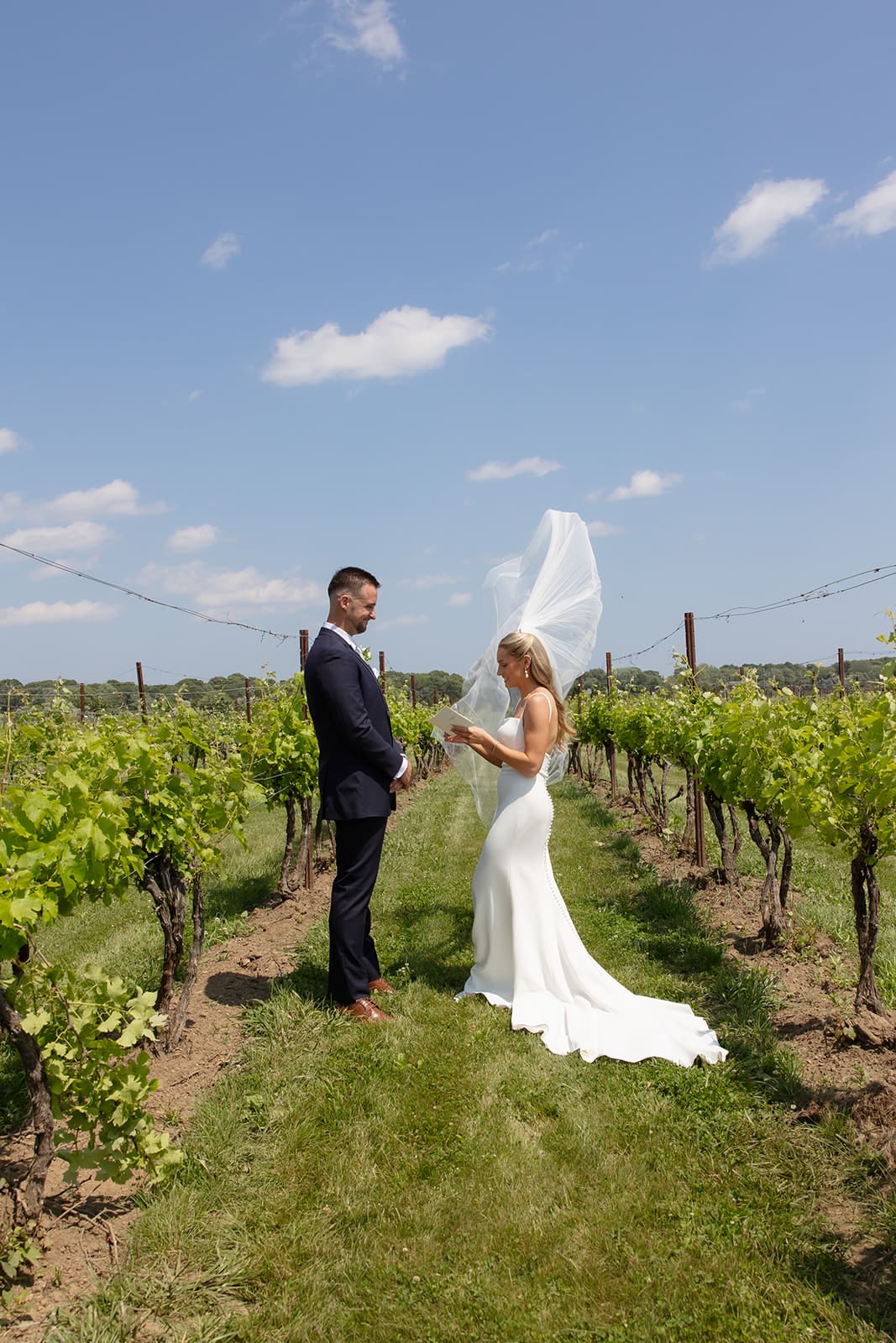 Bride reading private vows to groom between vineyard rows at a Connecticut wedding venue
