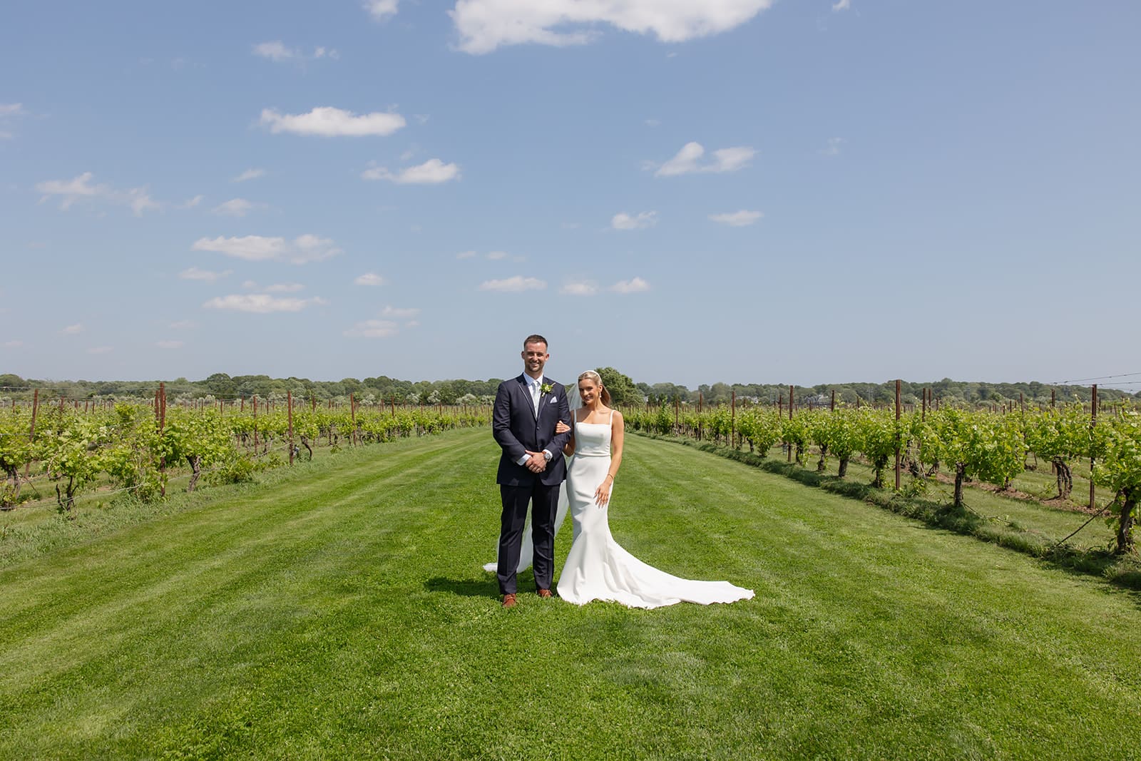Bride and groom standing together for portraits between vineyard rows at a Connecticut wedding venue
