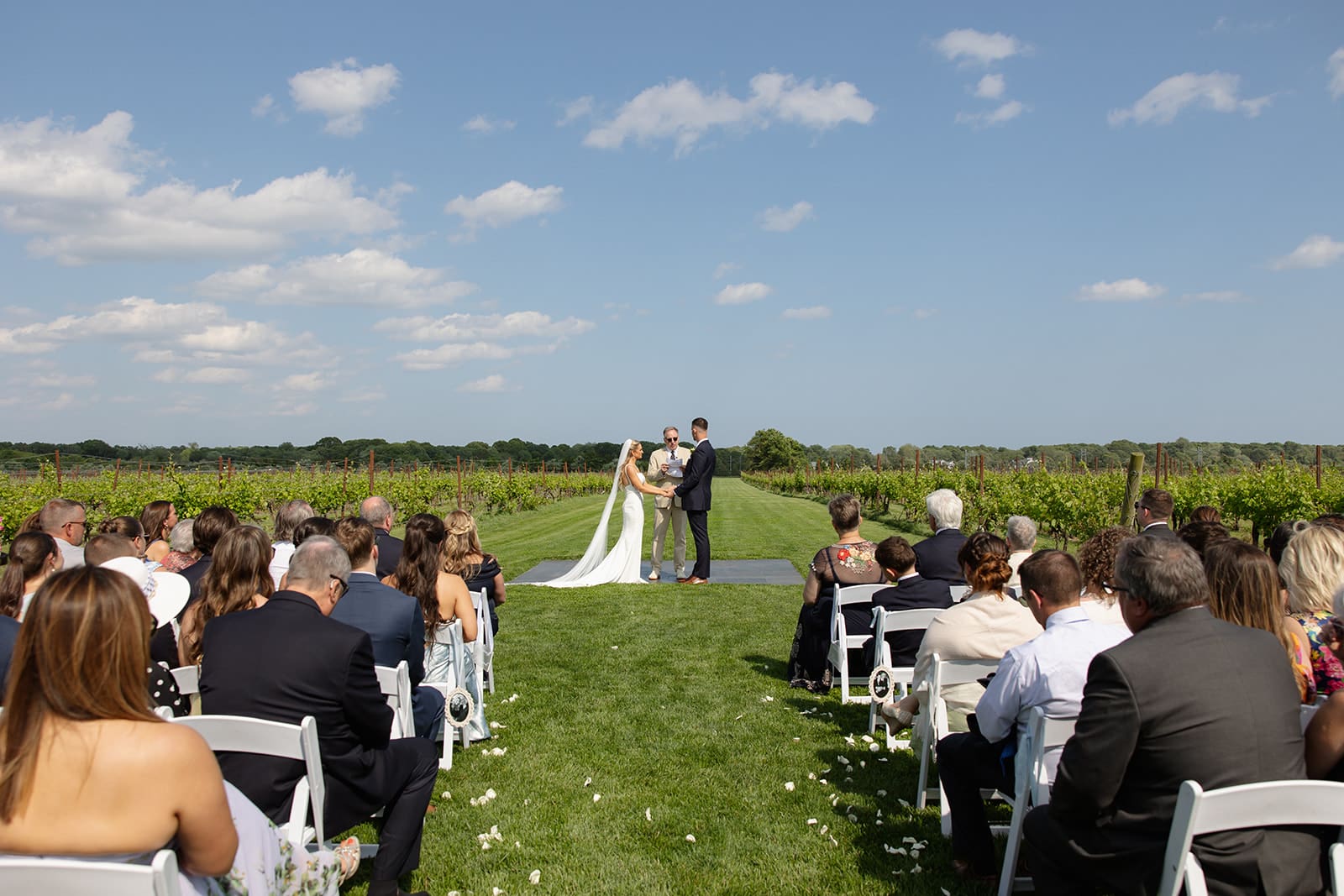 Outdoor wedding ceremony with guests seated beside vineyard rows at a Connecticut wedding venue
