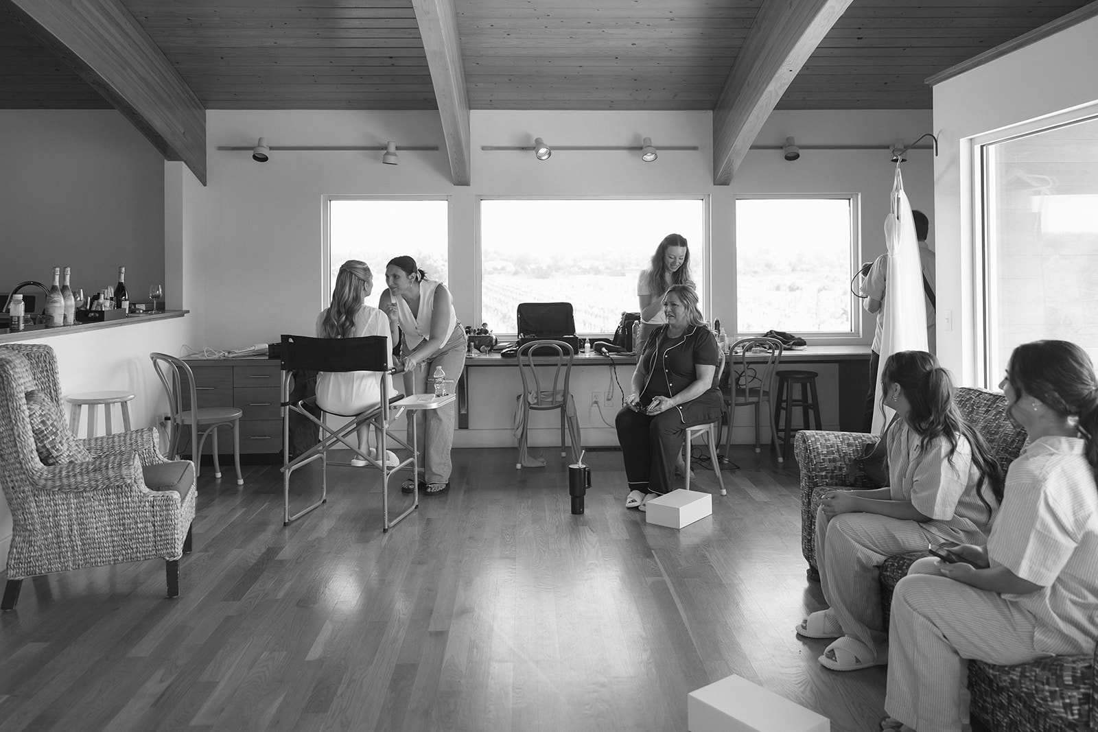 Black and white photo of bridesmaids getting ready together in a spacious bridal suite.
