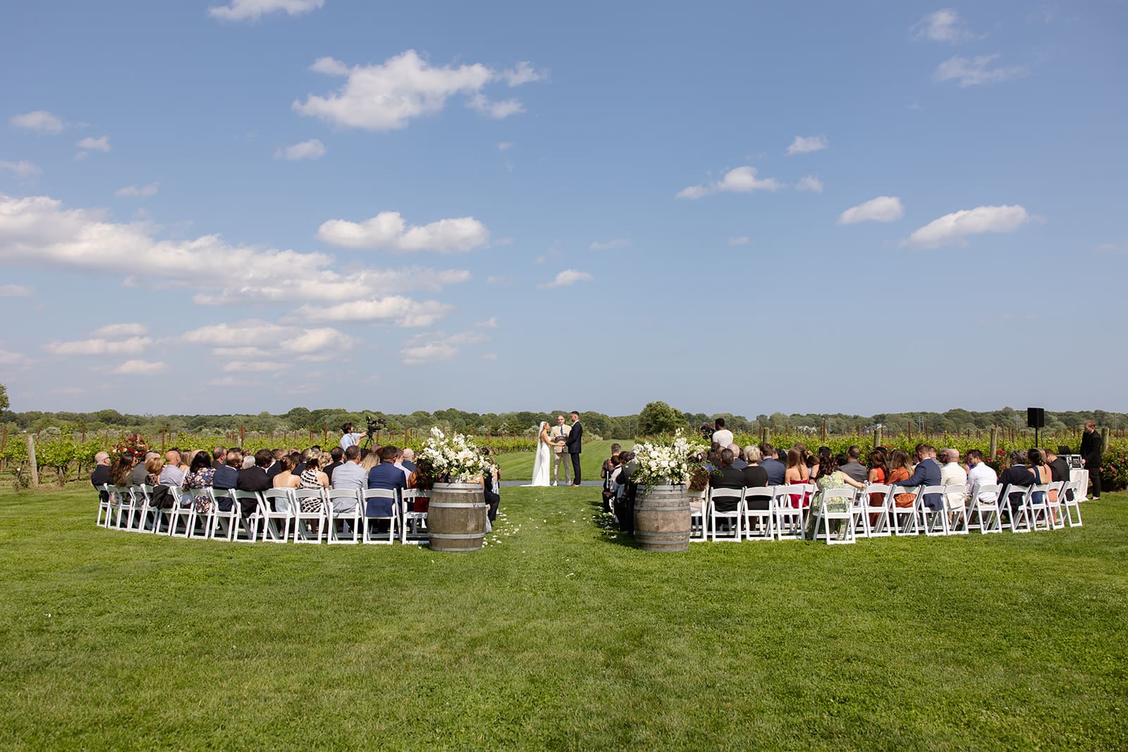 Wide view of vineyard ceremony with guests seated on lawn at a Connecticut wedding venue
