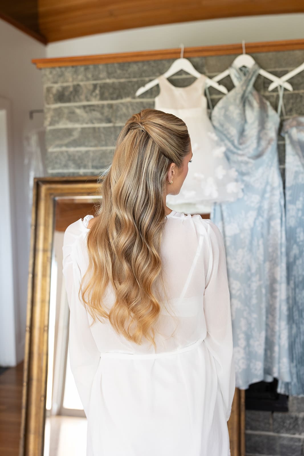Bride looking at bridesmaid dresses hanging in bridal suite before getting ready
