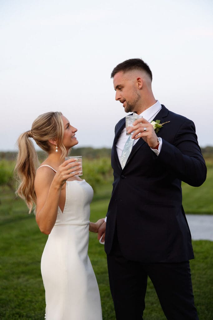 Bride and groom toasting drinks together during sunset portraits at a Connecticut wedding venue
