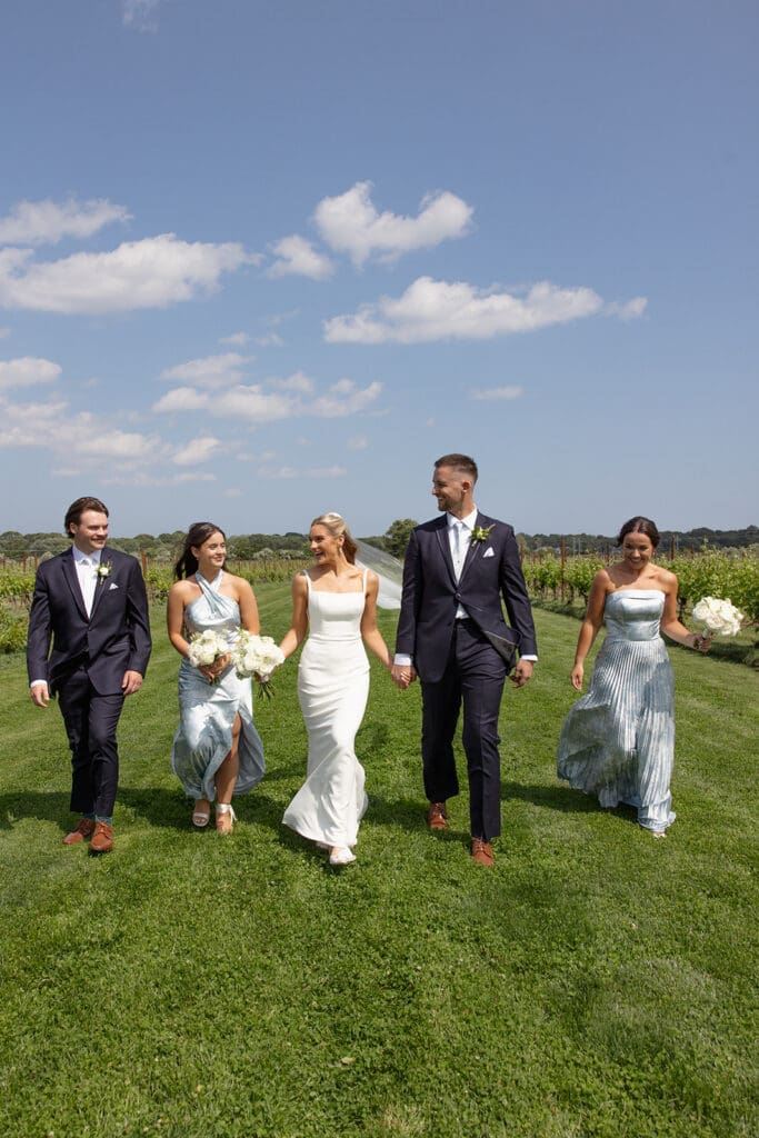 Bride, groom, and wedding party walking through vineyard rows at a Connecticut wedding venue

