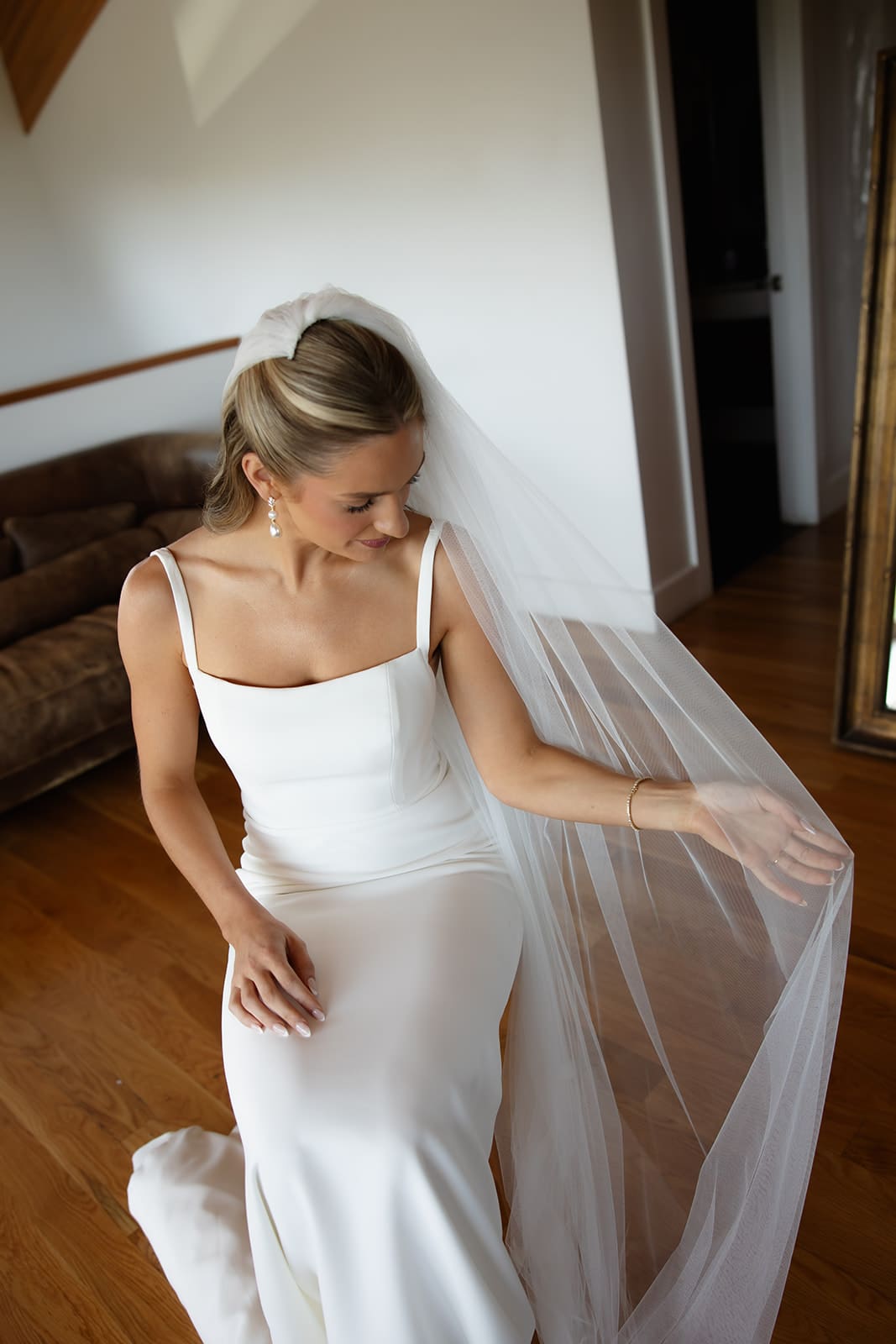 Bride adjusting veil while sitting in bridal suite before ceremony
