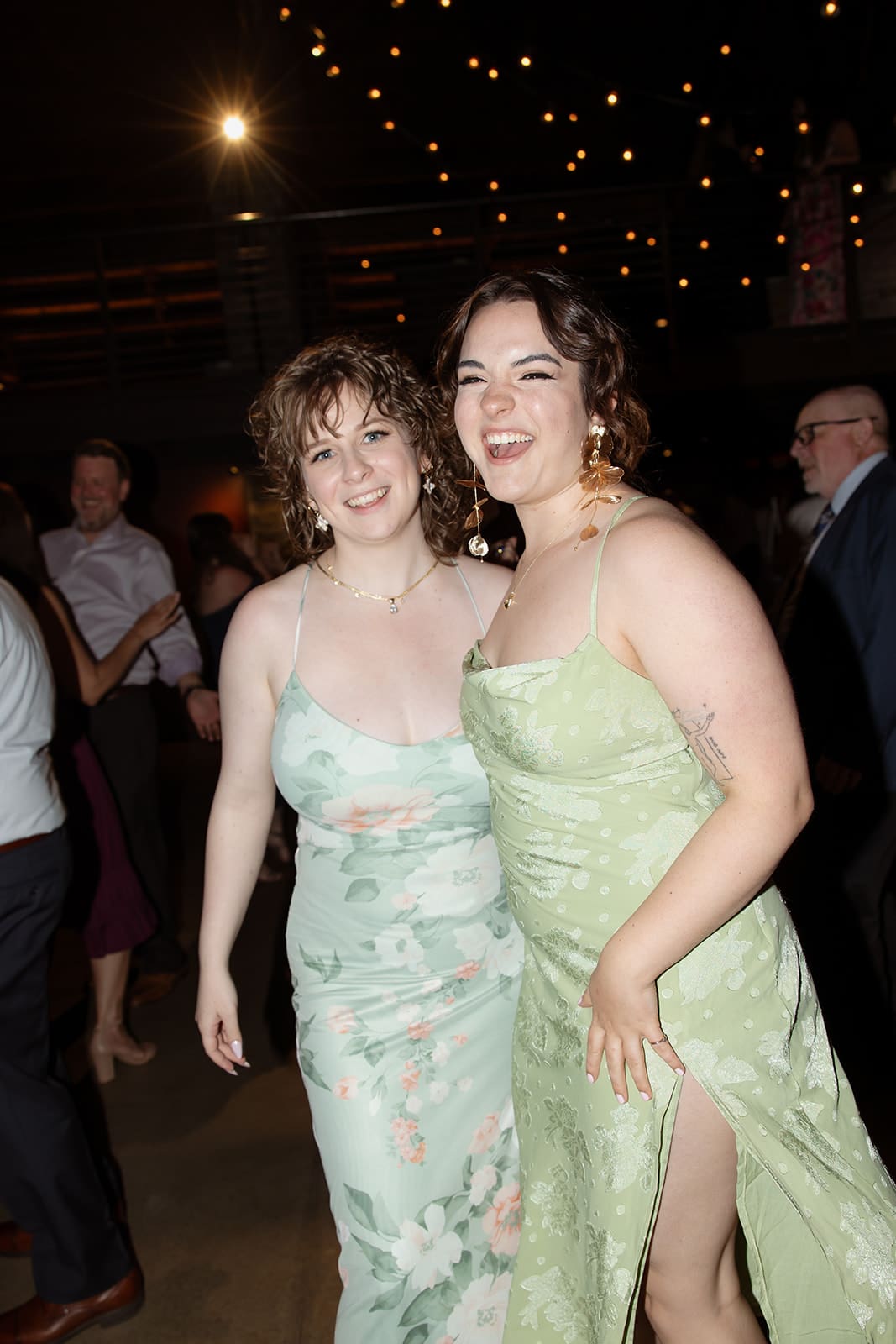 Wedding guests dancing together on the reception dance floor under warm string lights.