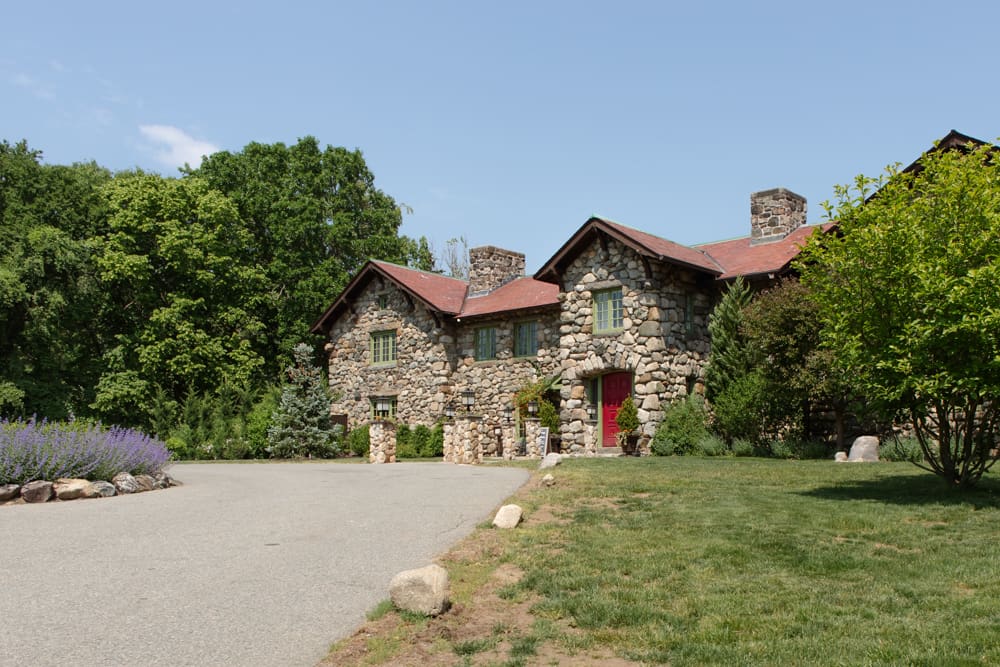 Wide view of a historic stone estate surrounded by greenery, a classic Massachusetts wedding venue
