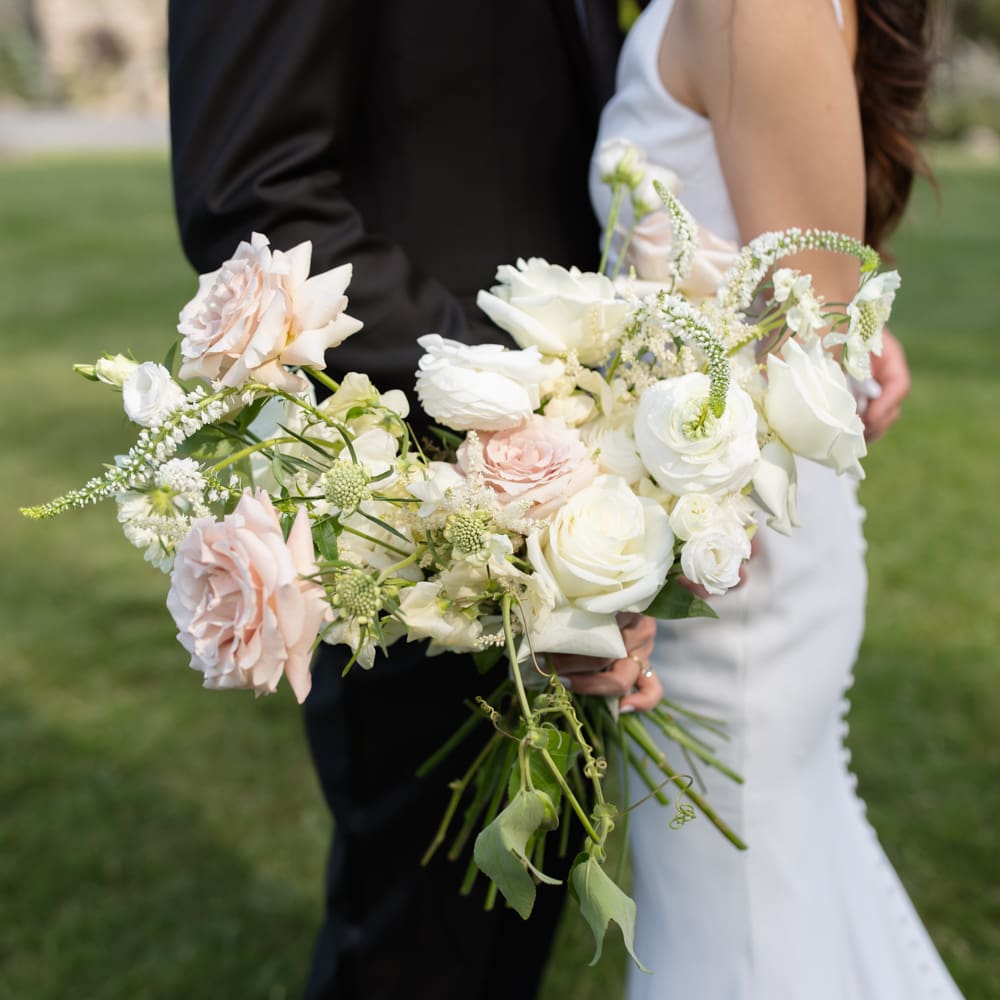 Close-up of a soft, organic bridal bouquet with white and blush garden roses and trailing greenery