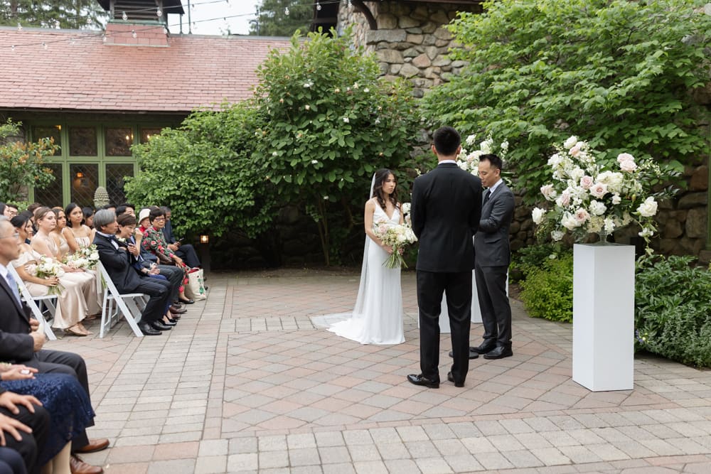 Intimate ceremony moment with the couple standing together in a garden courtyard surrounded by guests at a Massachusetts wedding venue