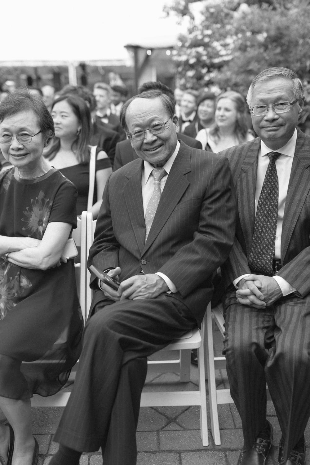 Wedding guests seated during the ceremony, smiling and watching from the front row in a courtyard at a Massachusetts wedding venue