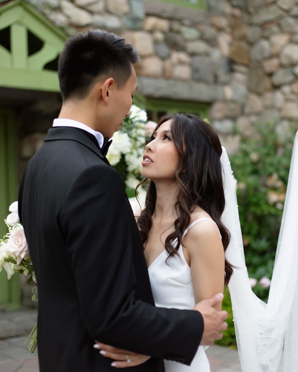 Close portrait of bride and groom embracing in front of a stone building at a Massachusetts wedding venue
