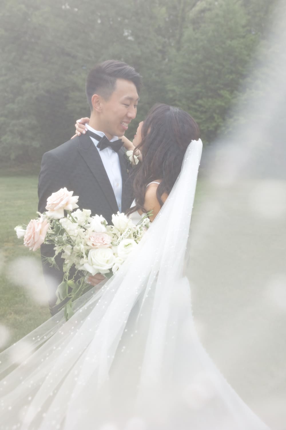 Romantic portrait of bride and groom with veil and bouquet, softly framed by light at a Massachusetts wedding venue
