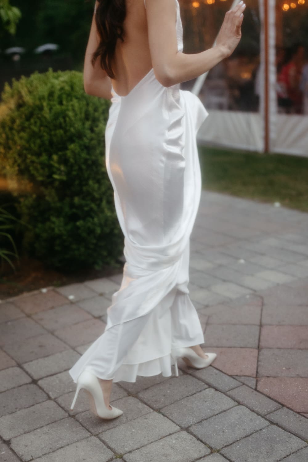 Bride walking across a stone patio in a fitted gown and heels during the reception at a Massachusetts wedding venue
