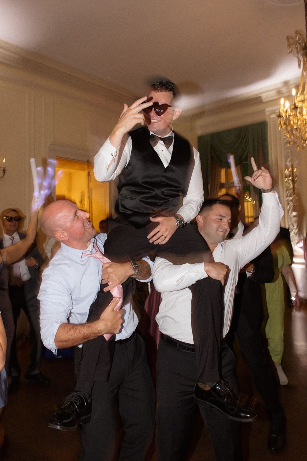 Groom being lifted on shoulders by friends on the dance floor during a lively reception at a wedding venue in Rhode Island.