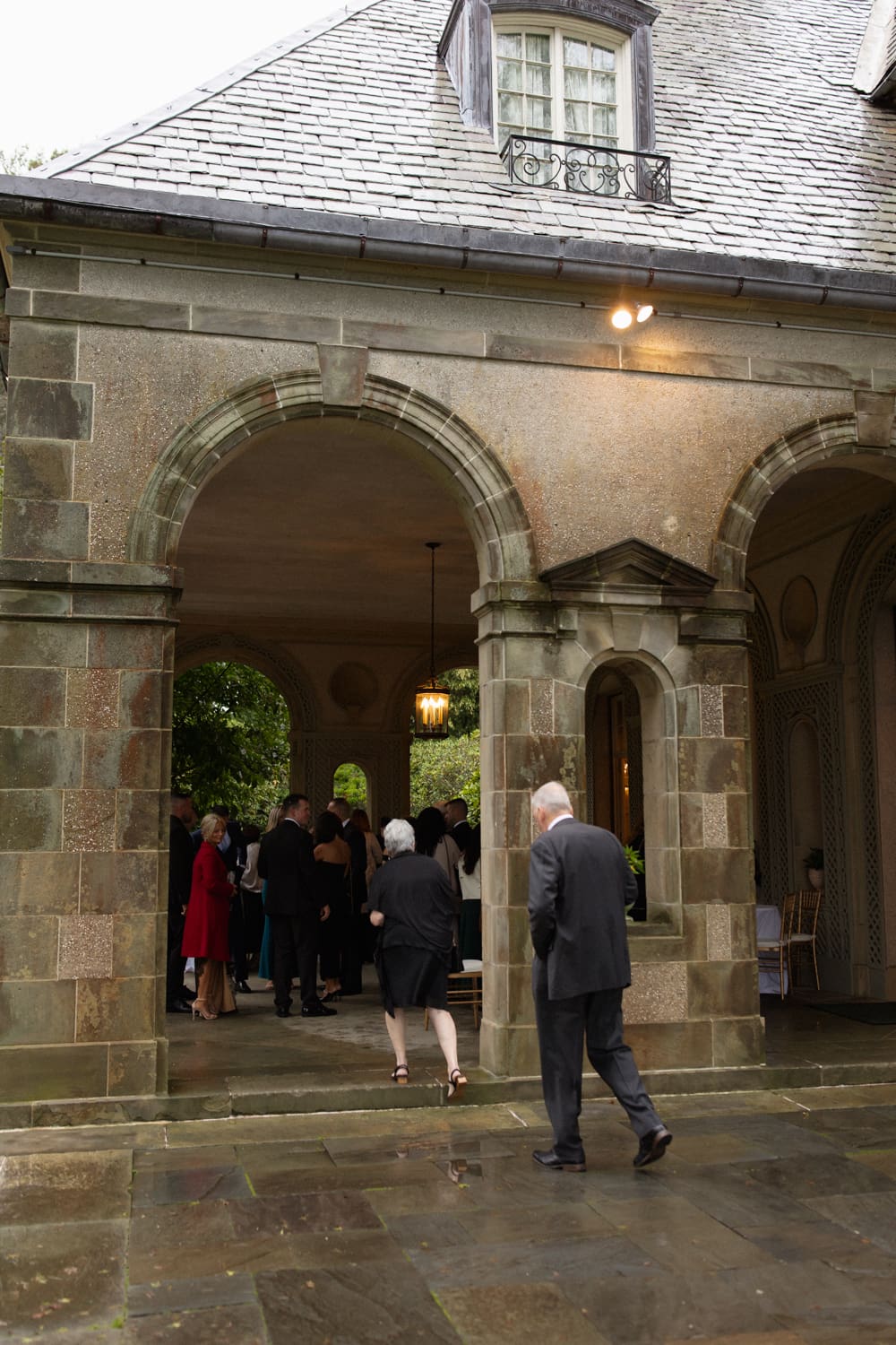 Guests walking into a covered stone entryway during cocktail hour.