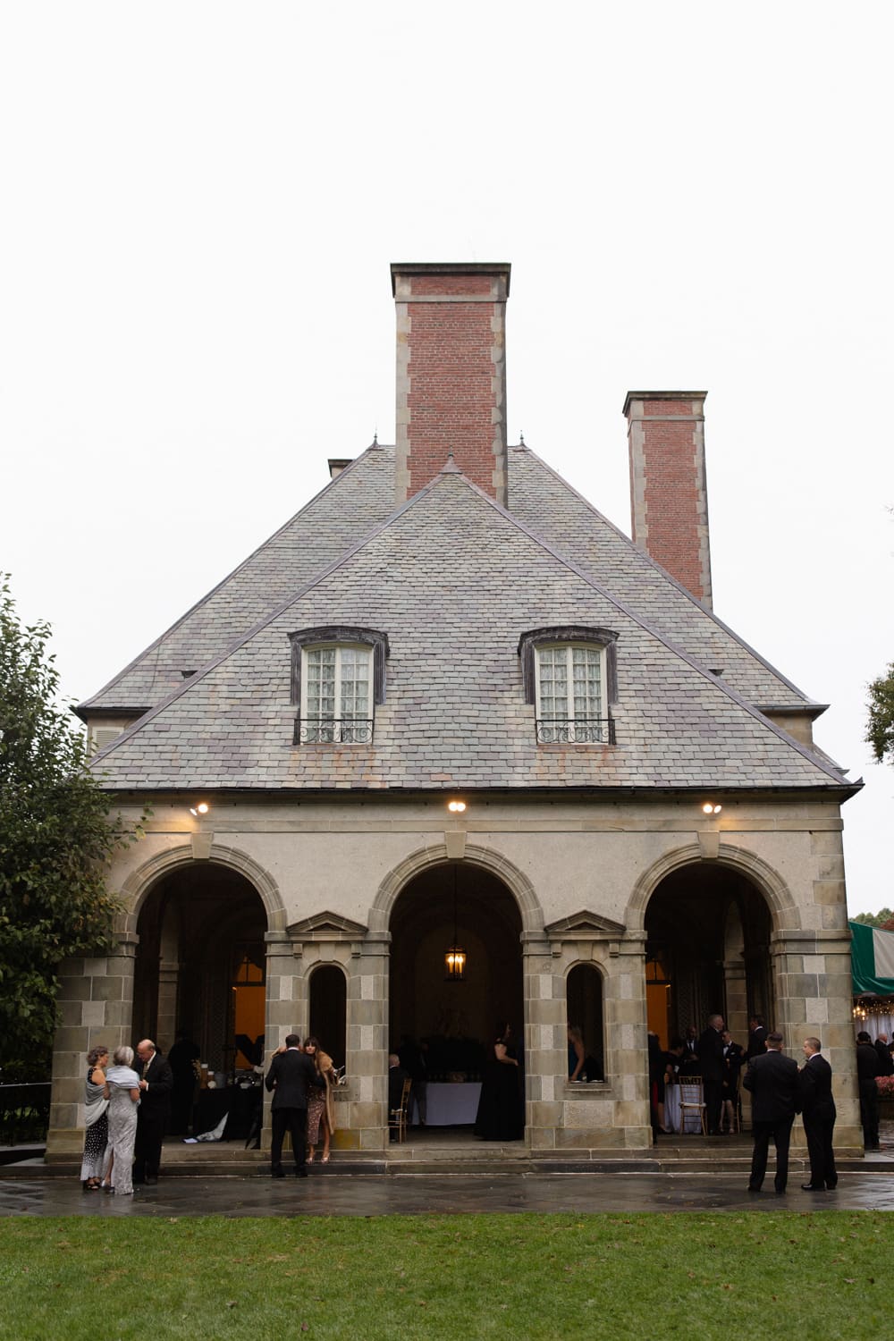 Guests gathered outside a stone building during cocktail hour at a wedding venue in Rhode Island.
